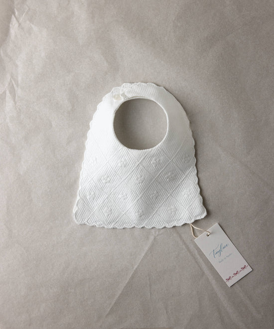 Babero de bebé de piqué blanco bordado Tinylace, presentado en packaging