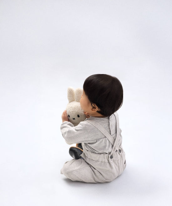 Bebé con pantalón de tirantes gris y peluche — Kala