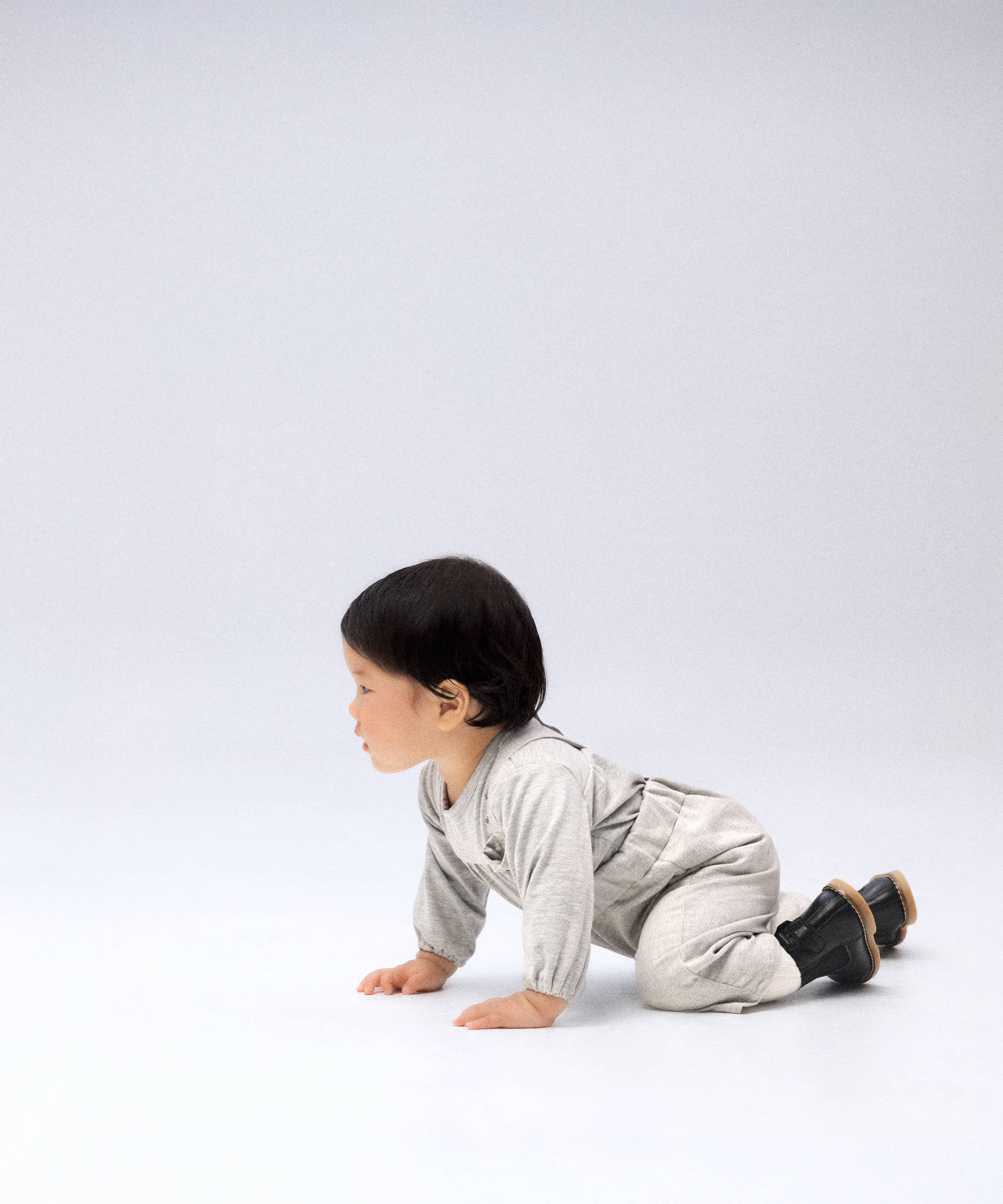 Bebé gateando con pantalón de tirantes gris — Kala