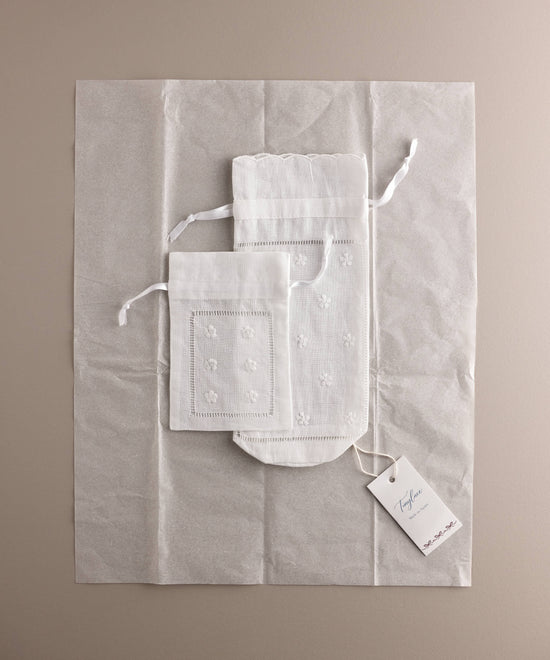 Set Tinylace de porta chupete y porta biberón en lino bordado presentado sobre papel de seda con etiqueta Made in Spain