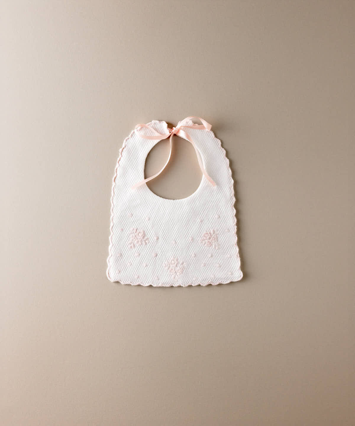 Babero de bebé de piqué blanco con flores y bodoques bordados en rosa y lazada de raso