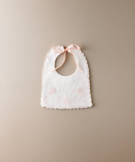 Babero de bebé de piqué blanco con flores y bodoques bordados en rosa y lazada de raso