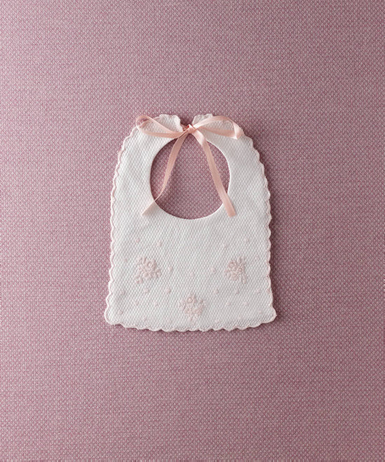 Babero de bebé Tinylace de piqué con flores bordadas en rosa sobre fondo rosa