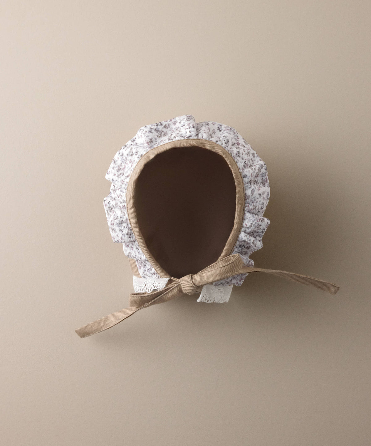 Interior de la capota de bebé de sarga avellana con volante floral y lazada al tono