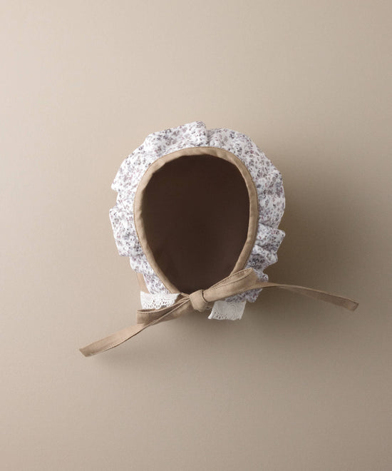 Interior de la capota de bebé de sarga avellana con volante floral y lazada al tono