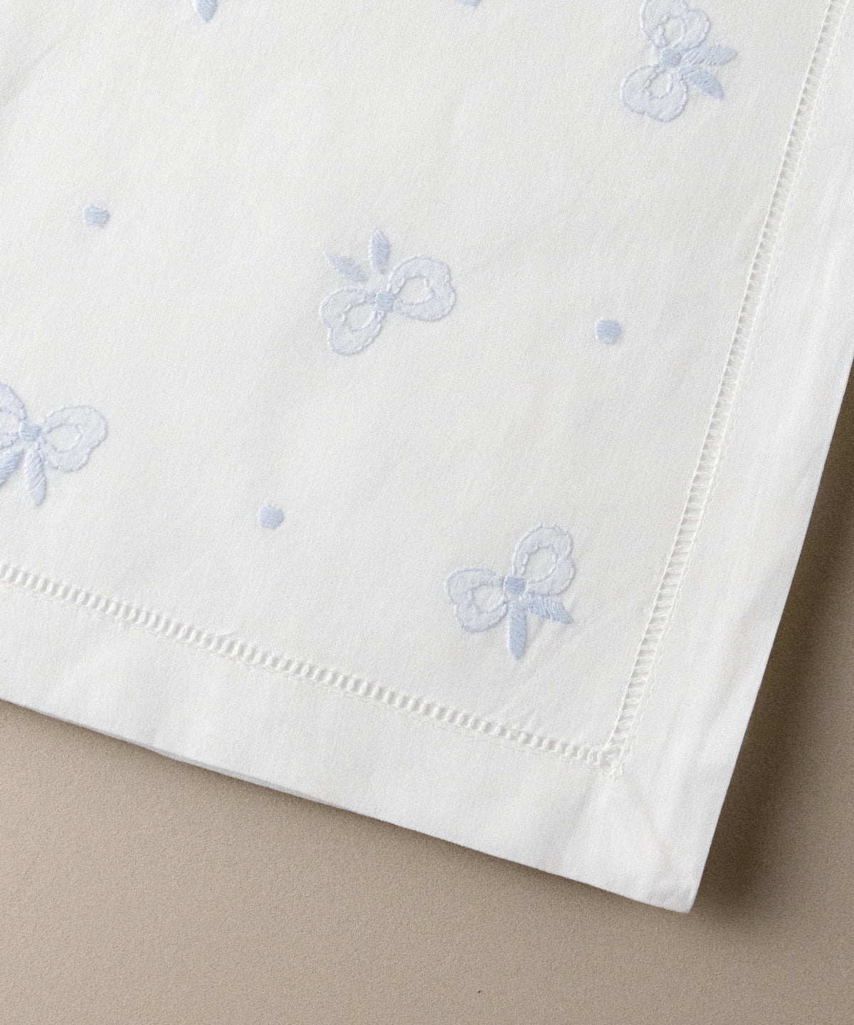 Detalle de los lazos bordados en azul celeste en punto de sombra, con vainica calada