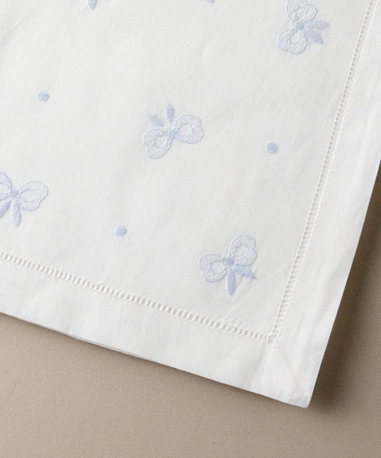 Detalle de los lazos bordados en azul celeste en punto de sombra, con vainica calada