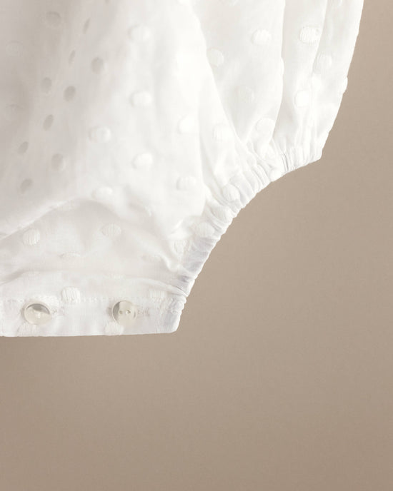 Detalle de los broches de nácar en la entrepierna de un pelele de bebé de bodoques bordados en blanco, tejido de algodón bordado, ropa de bebé artesanal hecha en España Tinylace