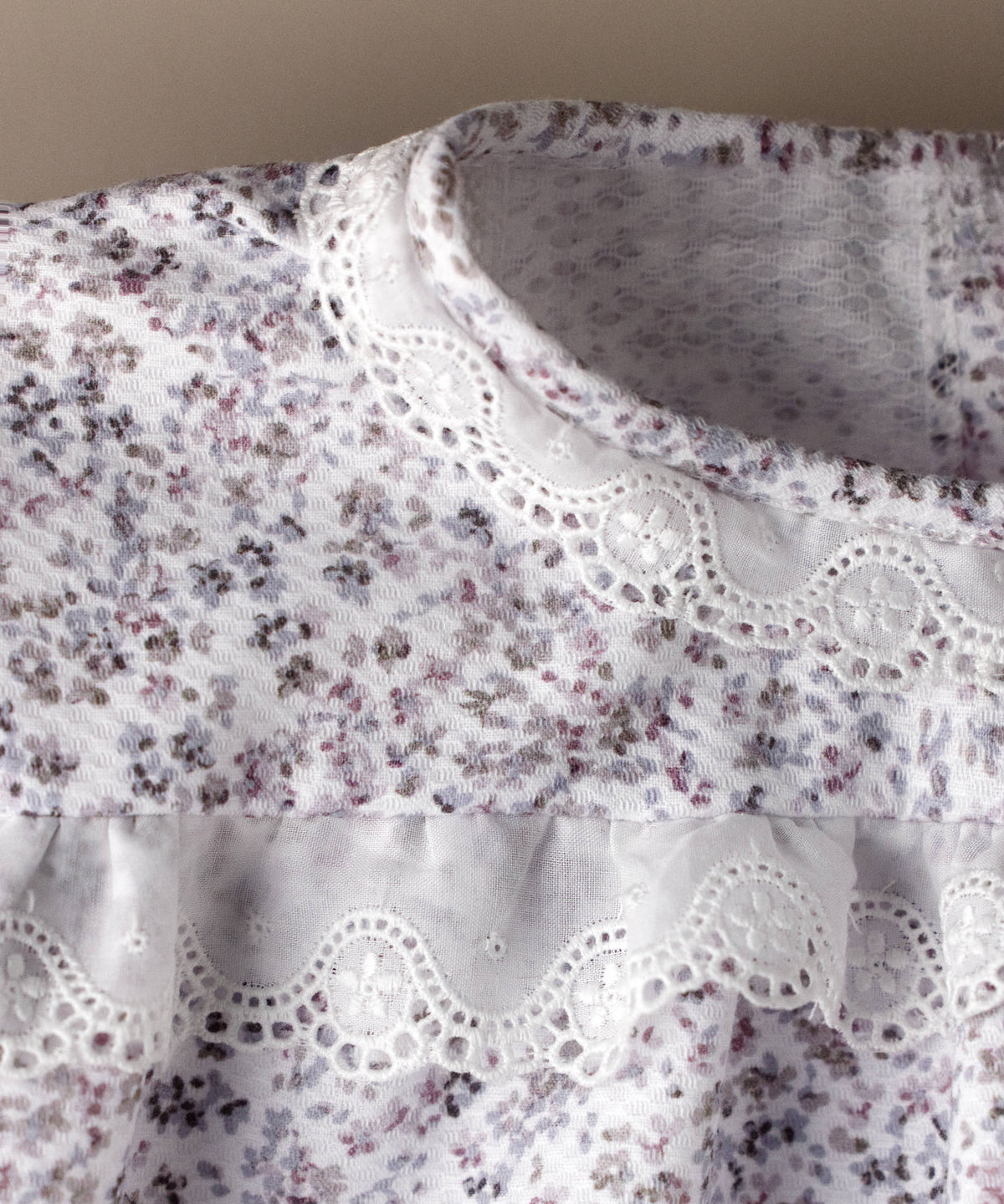 Detalle de la tira bordada broderie en el canesú del pelele de piqué floral